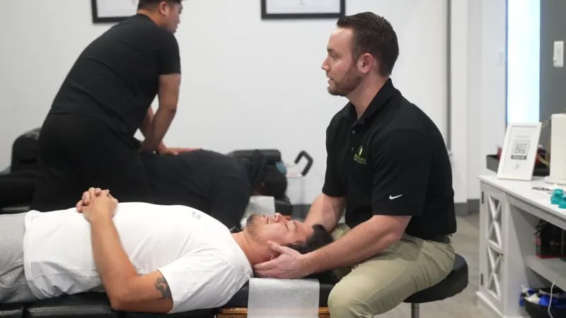 Two RxWellness Spine and Health chiropractors performing spinal adjustments on patients in a modern treatment room, demonstrating the hands-on chiropractic care to look for when choosing a recommended chiropractor near you.