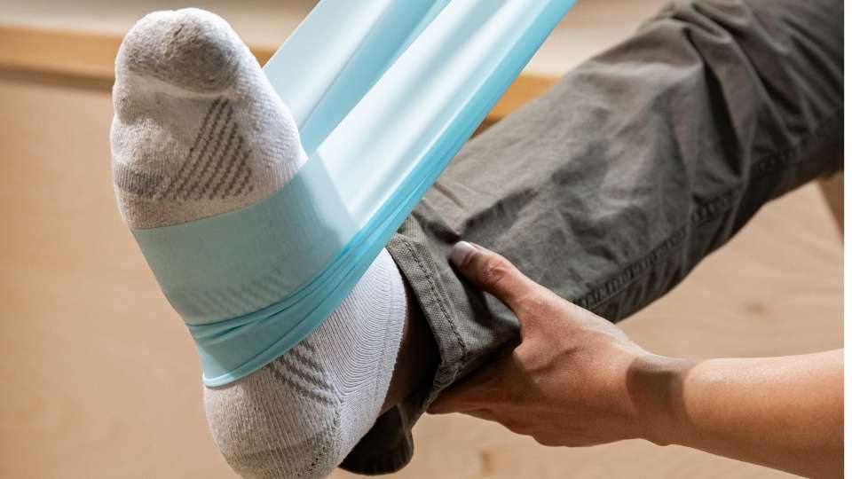 Person using a resistance band around their foot for ankle strengthening exercises during sprained ankle recovery