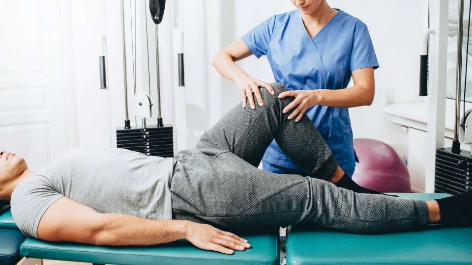 Chiropractor performing a lower leg and knee assessment on an athlete during a sports injury evaluation, using evidence-based chiropractic protocols to assess mobility, joint function, and movement patterns.
