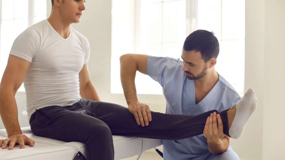 Chiropractic professional guiding an athlete through a knee mobility exercise during sports injury rehabilitation, following evidence-based chiropractic protocols to support movement, flexibility, and functional recovery.