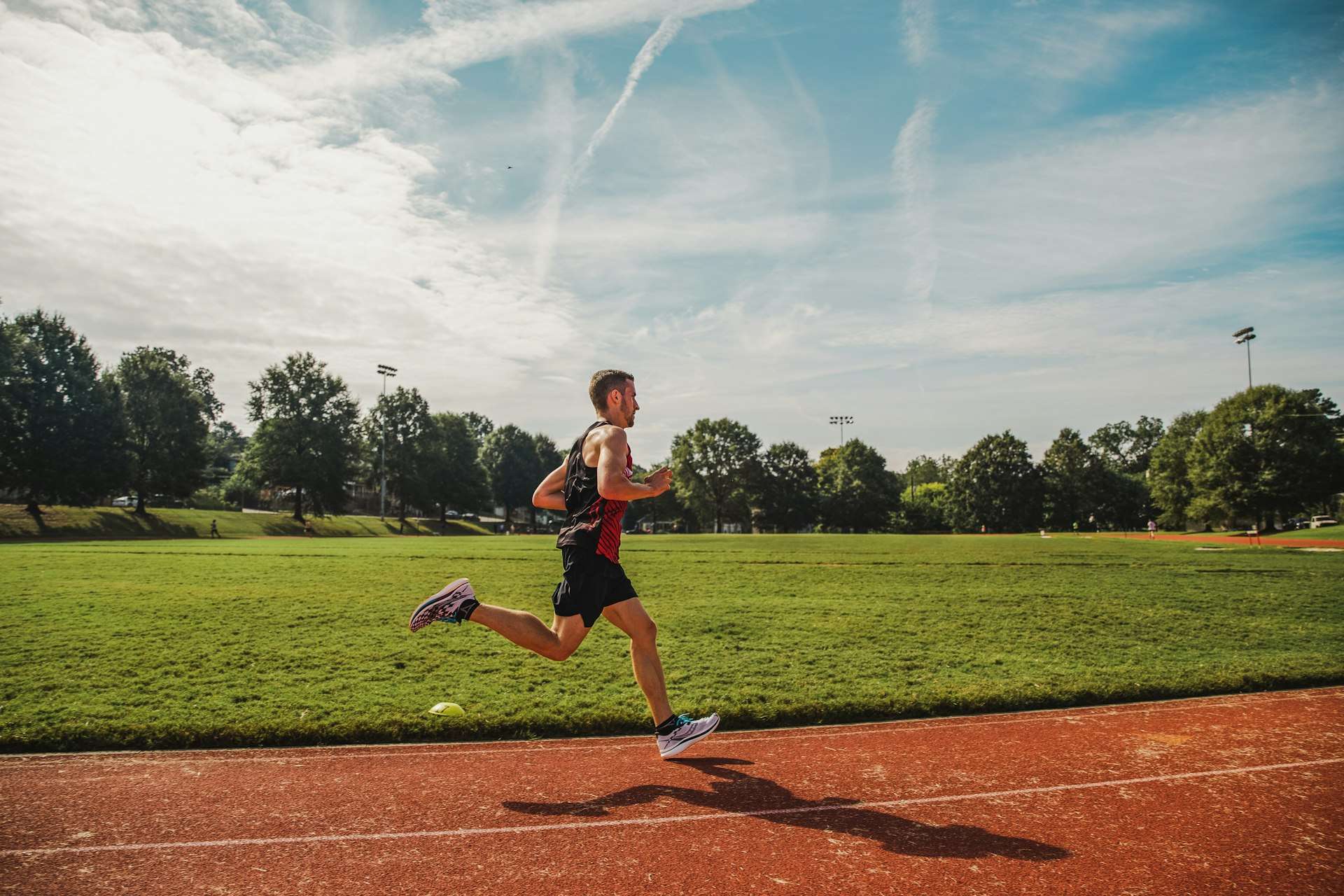 Runner working down an outdoor track, the sprinting and kicking load that produces most quadriceps strain injuries.