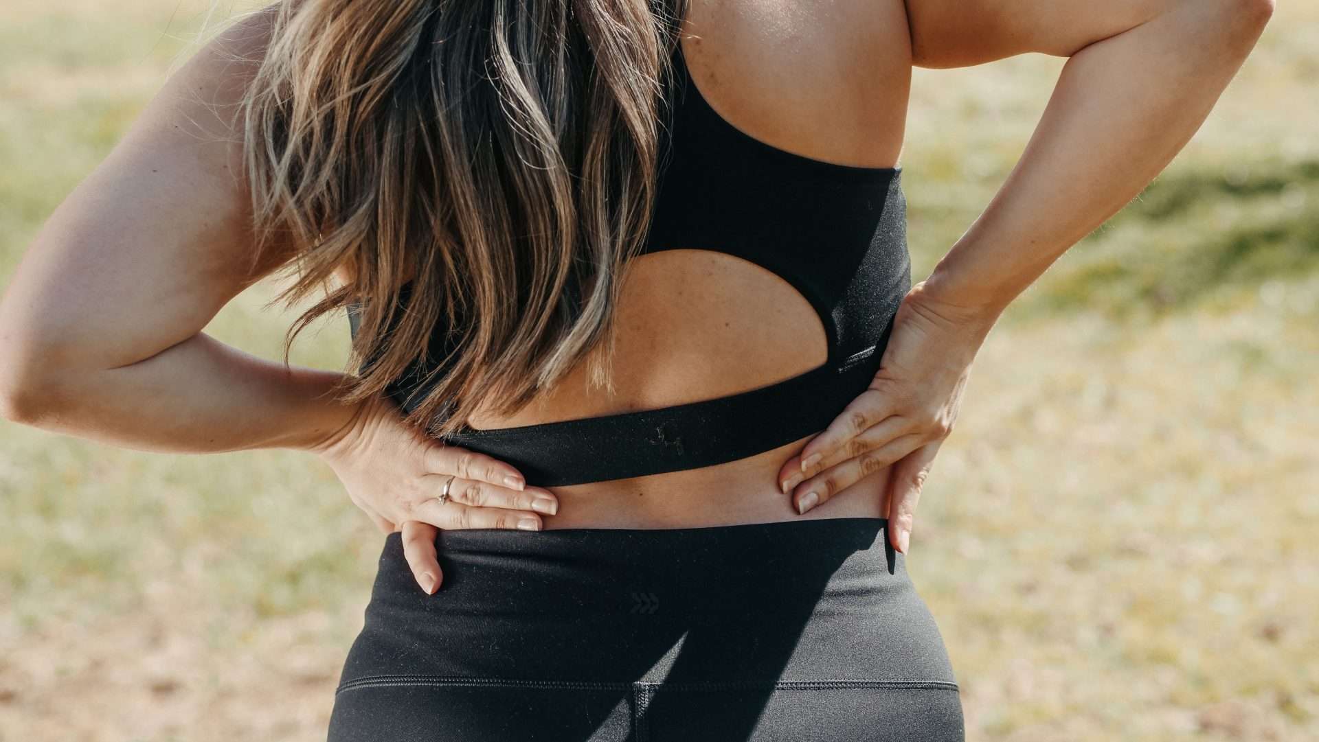 Adult holding their lower back, illustrating lower back strain discomfort.