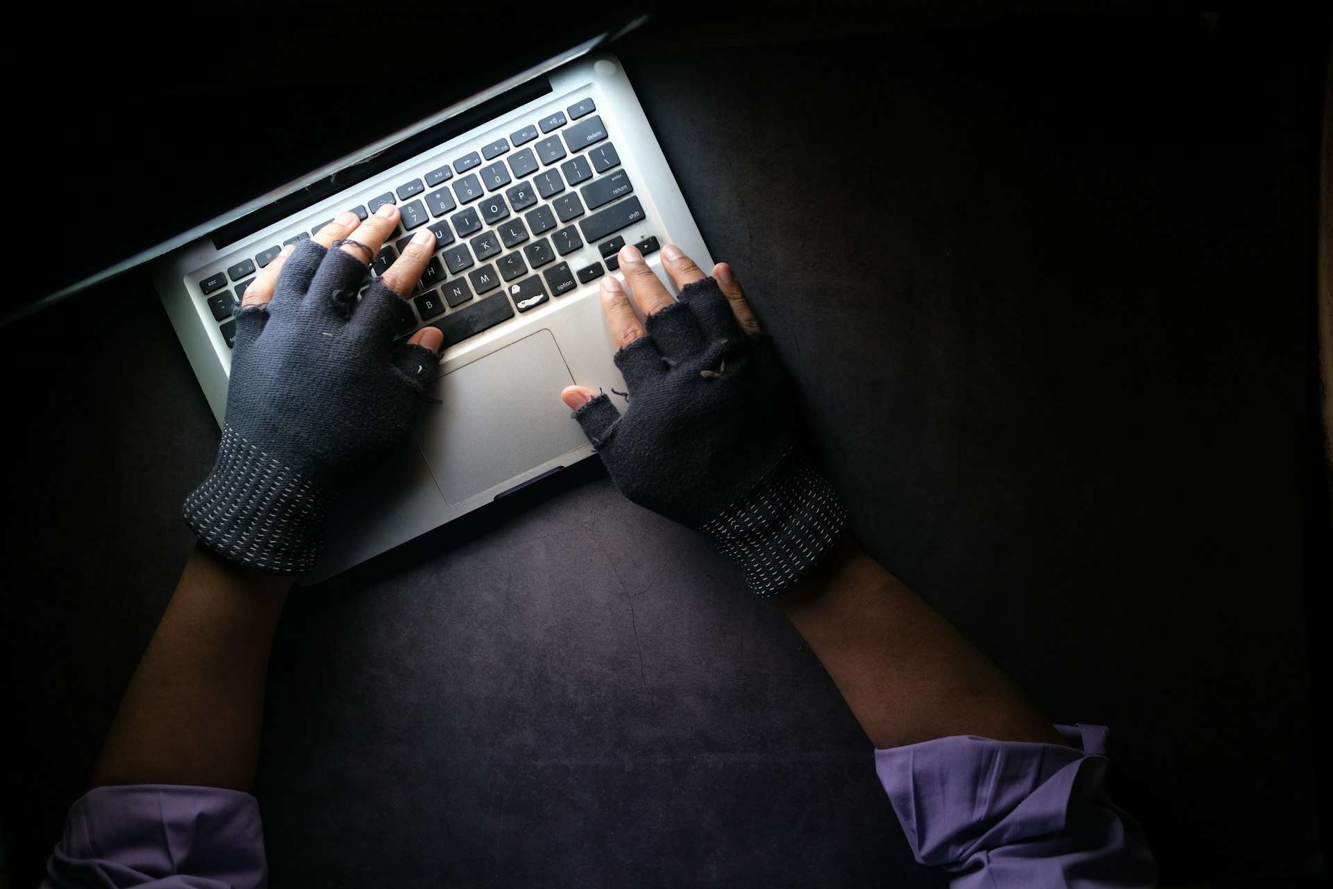Hands wearing black wrist supports type on a laptop keyboard, a common setting for carpal tunnel in Herndon and hand numbness.