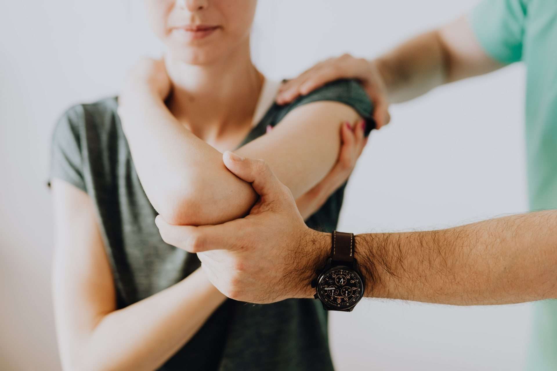 Chiropractor holds a patient's bent arm to test strength and joint motion during a screening exam for neck nerve symptoms