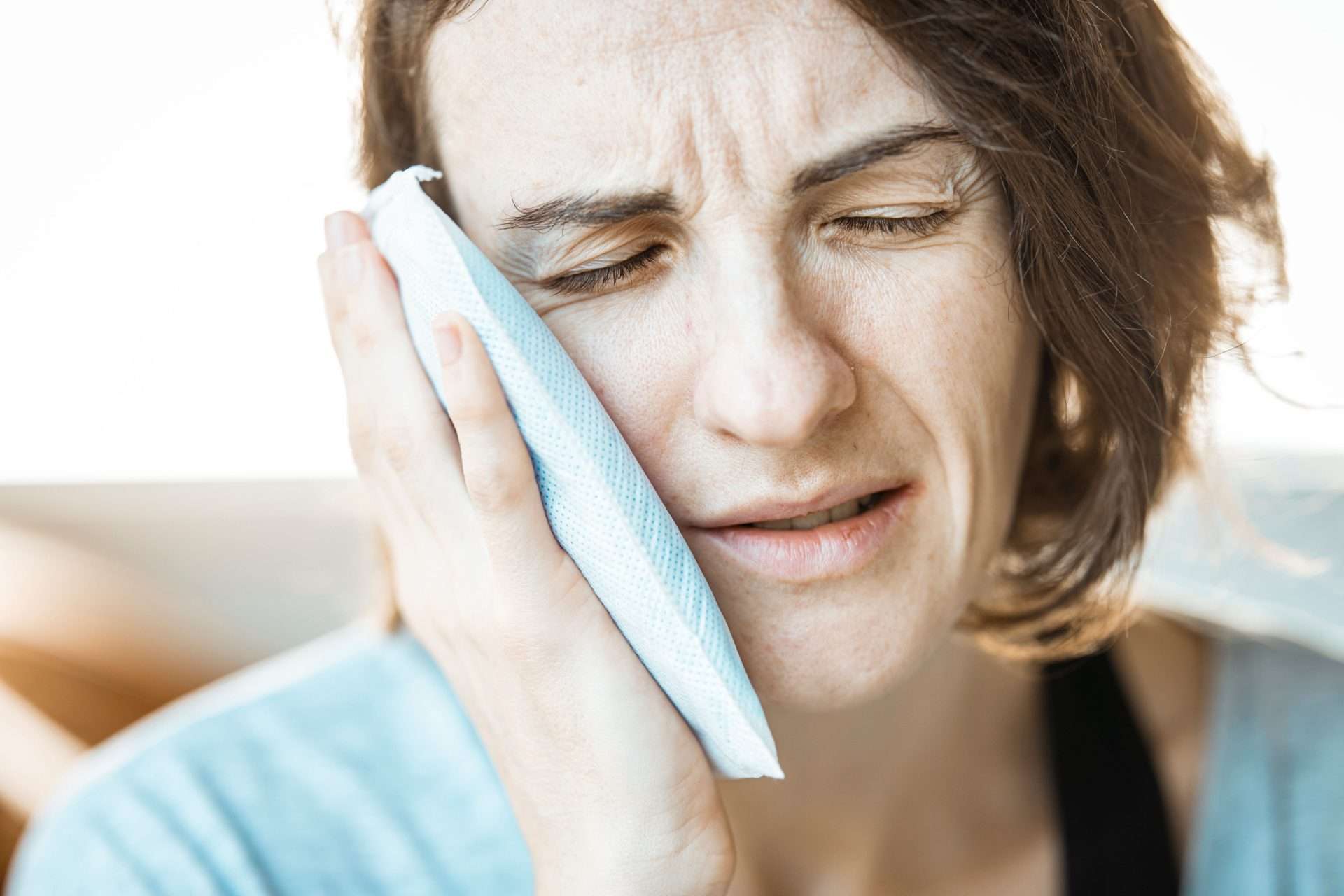 Woman applying a cold compress to her jaw to ease discomfort