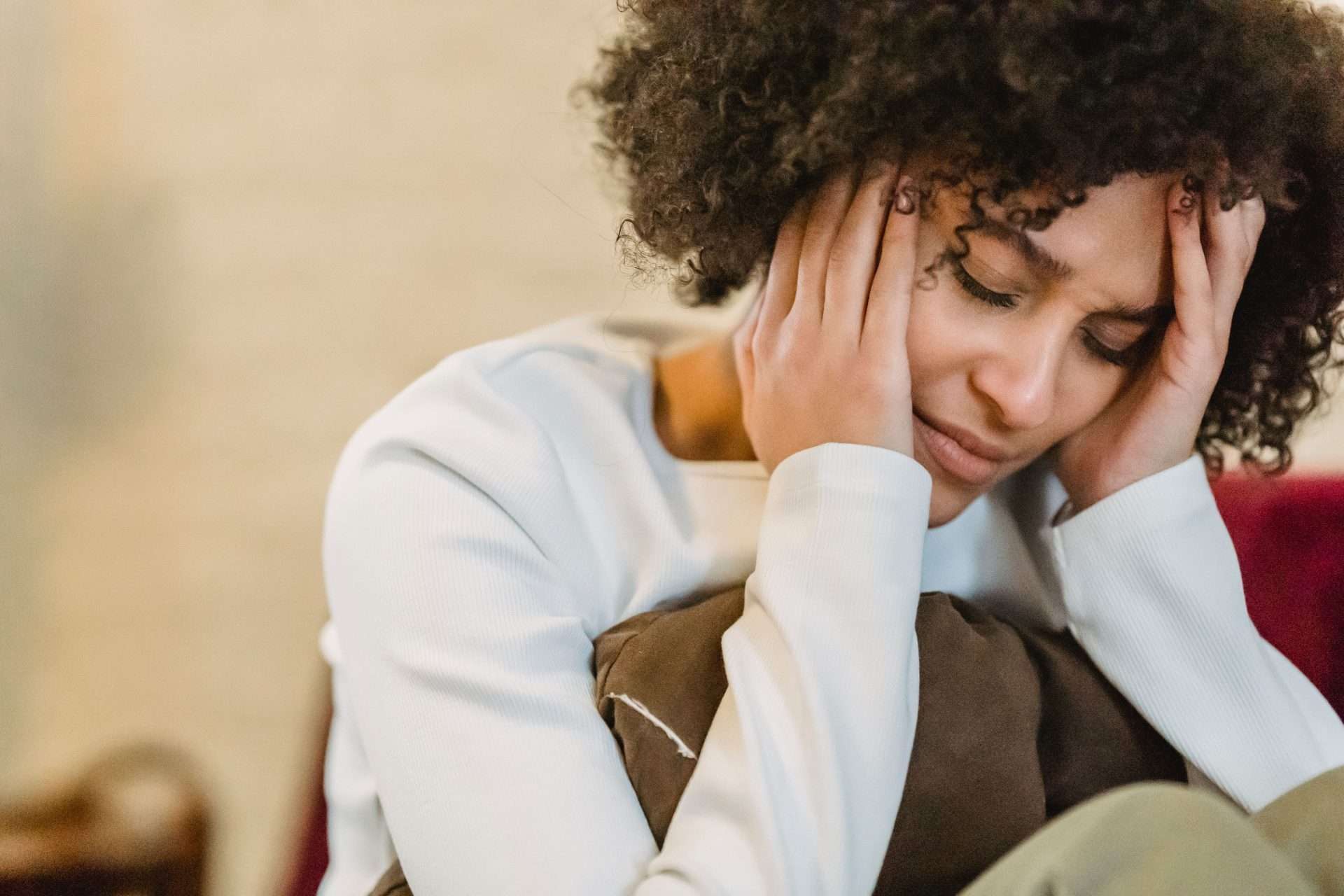 Woman holding her head with a headache, a symptom that can follow concussion or whiplash