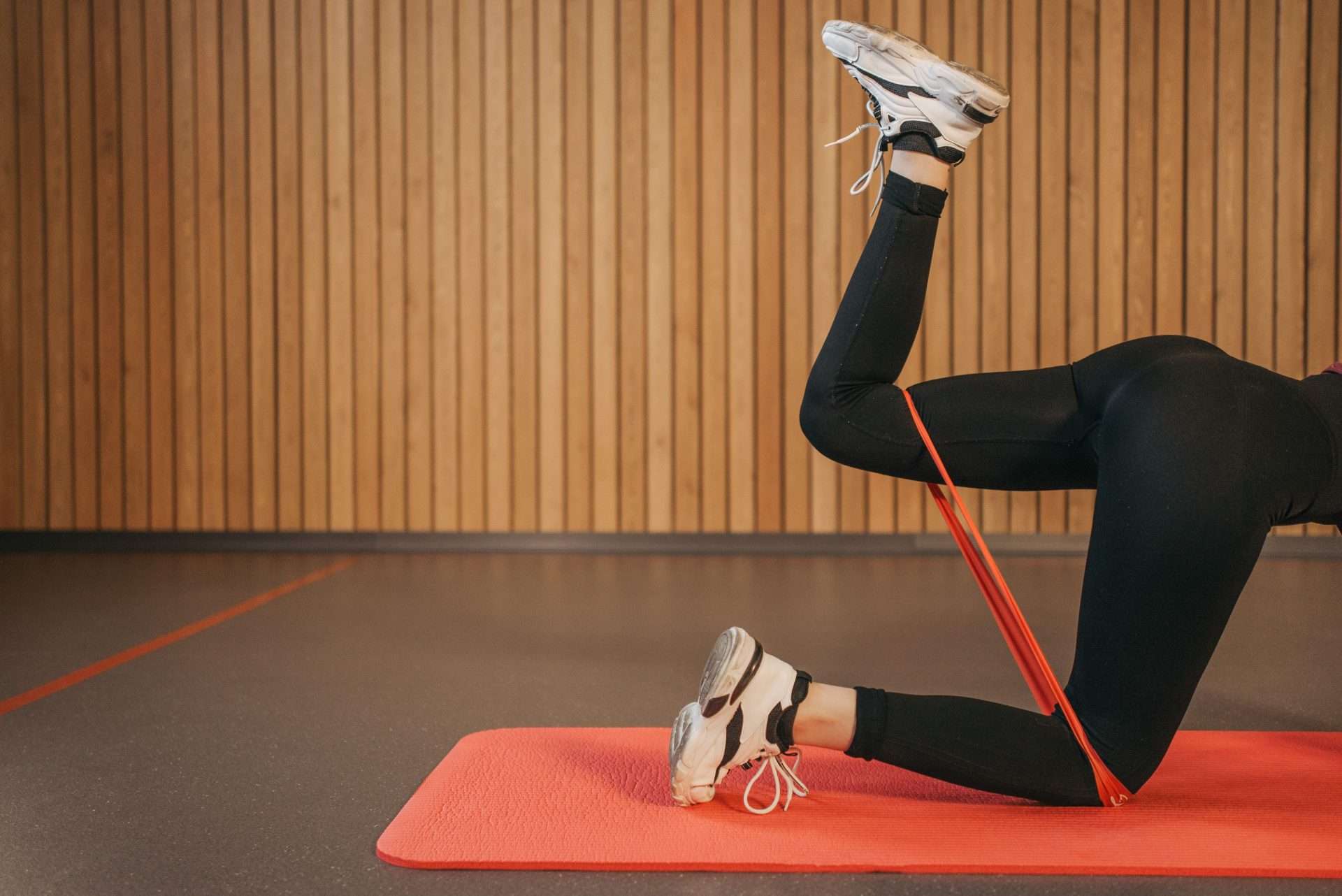 Woman doing a leg strengthening exercise with a resistance band on a mat at home