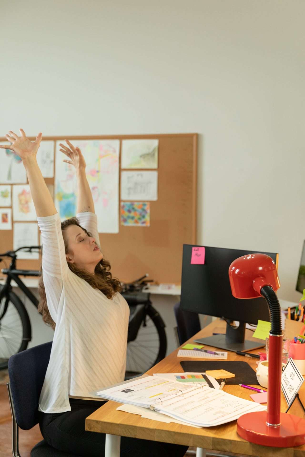 Woman stretching at her office desk while taking a short movement break from computer work