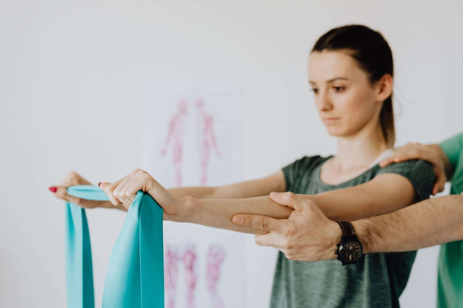 Clinician guiding a patient through a resistance band arm exercise as part of shoulder rehabilitation