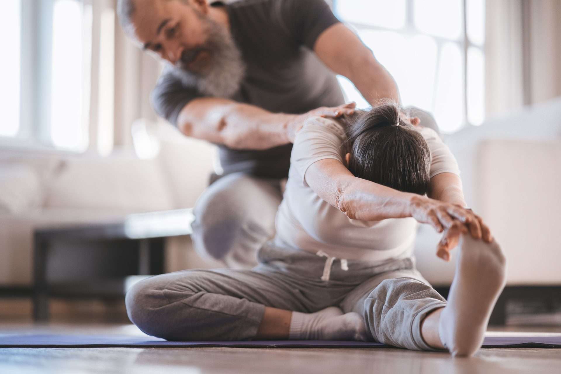 Person doing an assisted stretch on an exercise mat with guidance during a rehabilitation-style session